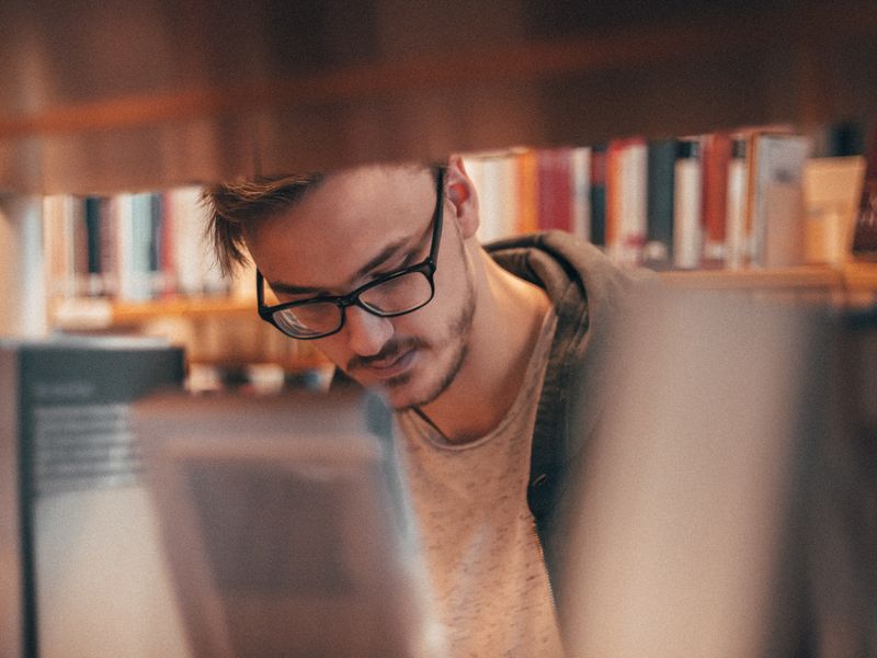 رجل يقرأ كتابًا في مكتبة هادئة بإضاءة دافئة
