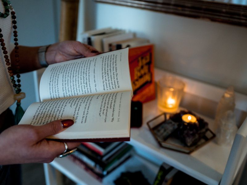 يدان تمسكان كتابًا بجوار شمعة مضيئة